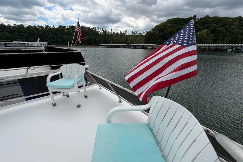 Slide: The Image of Houseboat deck with American flag, white chairs, and scenic lake view. STARDUST 16x70, 1988. - 47
