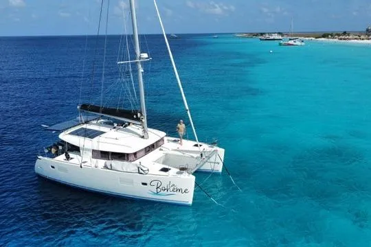 The Image of 2018 Lagoon 400 S2 catamaran sailing in clear turquoise waters near a sandy coastline. - 0