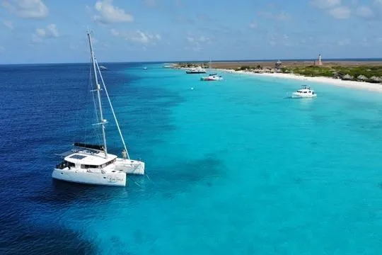 Slide: The Image of 2018 Lagoon 400 S2 catamaran anchored in clear turquoise waters near a sandy coastline. - 2
