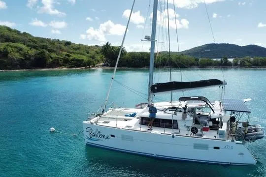 Slide: The Image of 2018 Lagoon 400 S2 catamaran anchored in clear turquoise waters near lush green shoreline. - 4