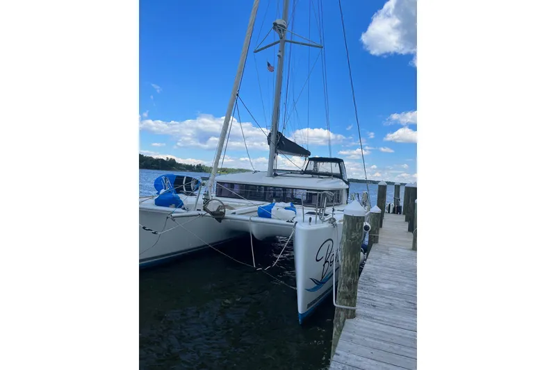 Slide: The Image of 2018 Lagoon 400 S2 catamaran docked by a wooden pier under a blue sky. - 6