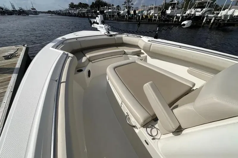 Slide: The Image of 2024 Boston Whaler 280 Outrage boat interior with beige seating, docked at marina. - 13