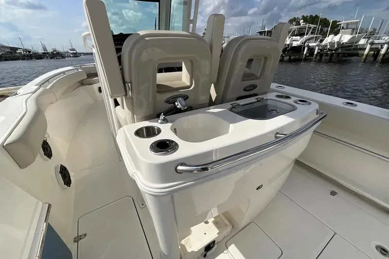 Slide: The Image of 2024 Boston Whaler 280 Outrage boat interior with sink and seating, docked at marina. - 5