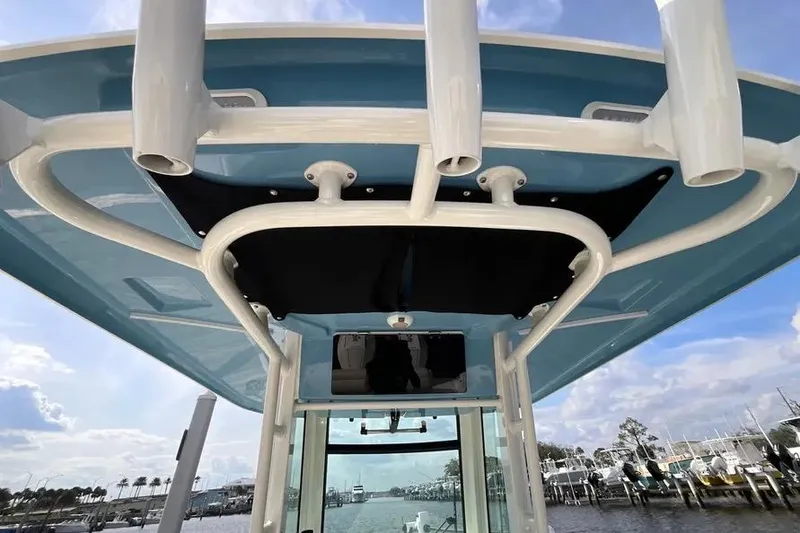 Slide: The Image of 2024 Boston Whaler 280 Outrage boat with blue canopy and rod holders, docked at marina. - 6