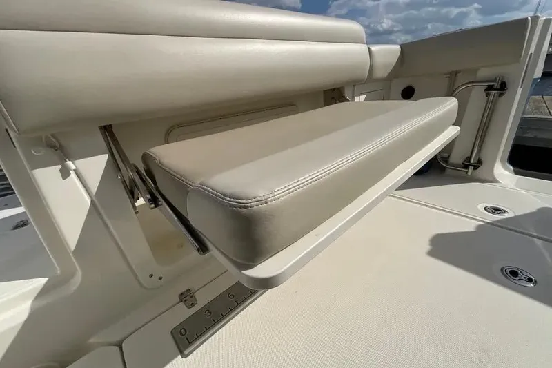Slide: The Image of 2024 Boston Whaler 280 Outrage foldable seat detail under sunny sky. - 7