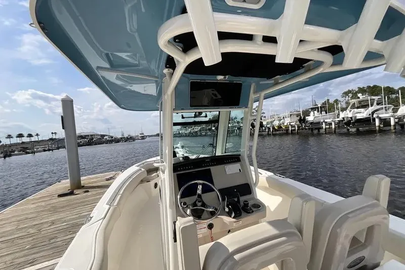 Slide: The Image of 2024 Boston Whaler 280 Outrage boat docked, showcasing helm and seating area. - 8