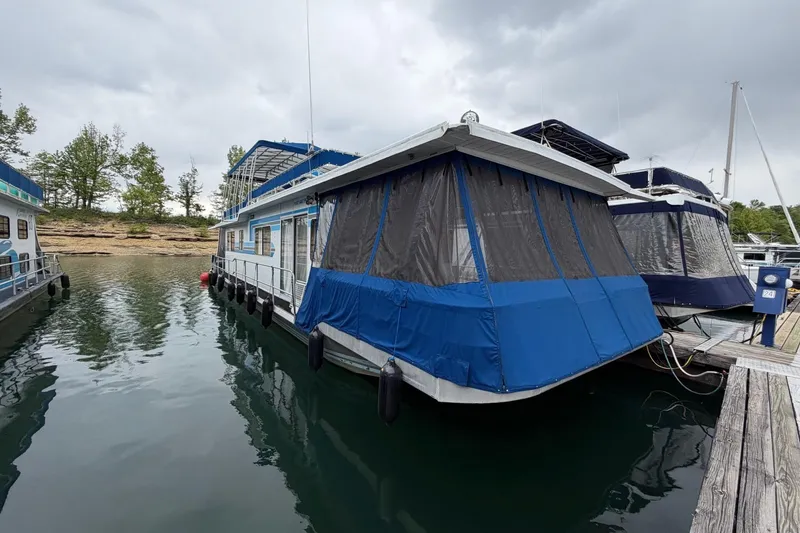 The Image of 1987 Jamestowner 14x60 houseboat docked on a calm lake under cloudy skies. - 0