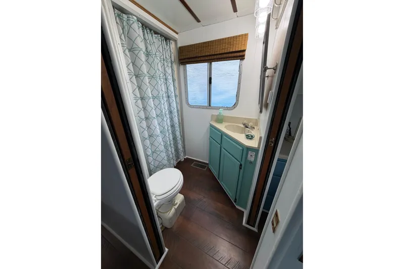 Slide: The Image of Bathroom interior of 1987 Jamestowner 14x60 houseboat with teal cabinets and shower curtain. - 21