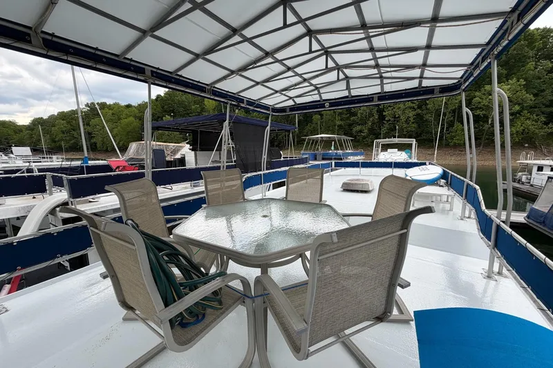 Slide: The Image of Houseboat deck with table and chairs, Jamestowner 14x60, 1987 model, docked by lush greenery. - 23