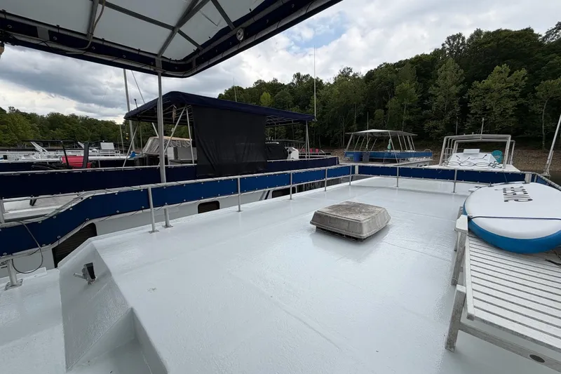 Slide: The Image of 1987 Jamestowner 14x60 houseboat deck with canopy, docked near lush green trees. - 25