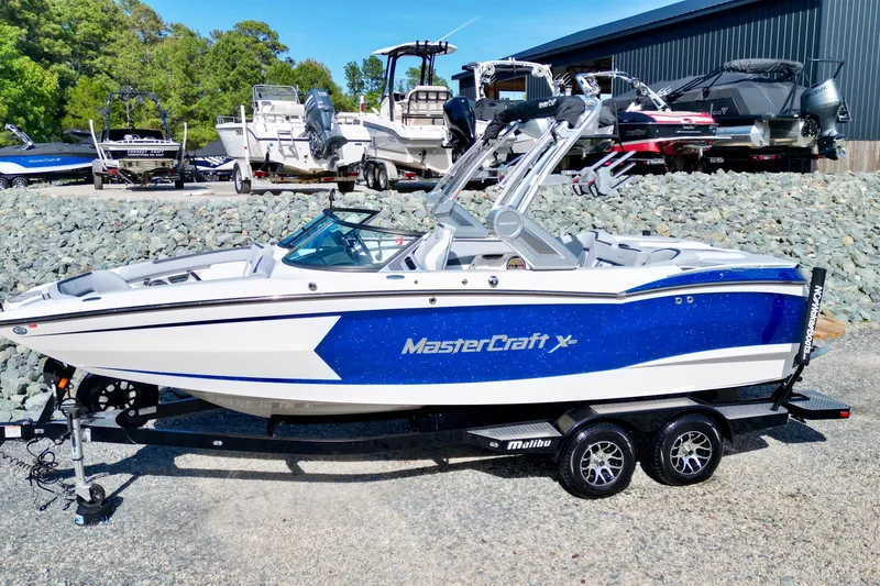 Slide: The Image of 2022 MasterCraft XStar boat with blue and white design on a trailer. - 3