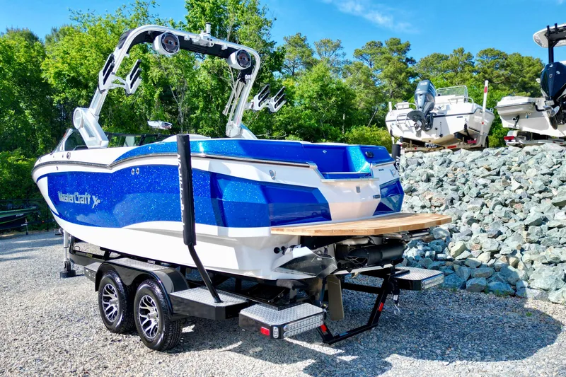 Slide: The Image of 2022 MasterCraft XStar boat on trailer, vibrant blue, parked outdoors. - 6