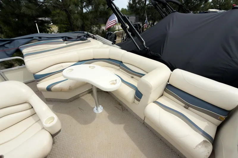 Slide: The Image of 2006 Bennington 2275RL boat interior with cream and blue seating, small table, and cup holders. - 5