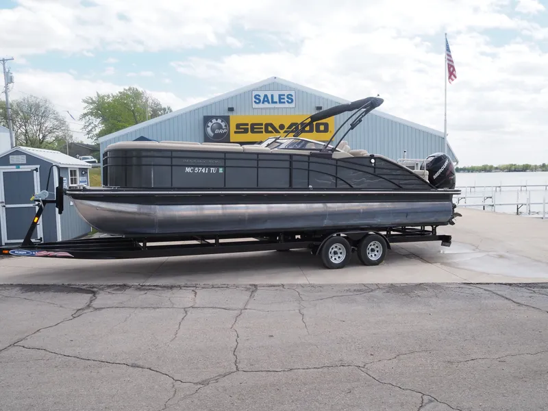 The Image of 2015 Bennington 2572 RCW pontoon boat on trailer outside sales building. - 1