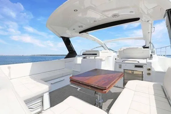 Slide: The Image of 2018 Cruisers Yachts 390 Express Coupe interior with sleek seating and wooden table on open water. - 18