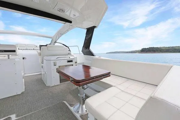 Slide: The Image of 2018 Cruisers Yachts 390 Express Coupe interior with elegant seating and table, overlooking serene waters. - 19