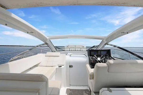 Slide: The Image of 2018 Cruisers Yachts 390 Express Coupe interior with helm and seating, on open water. - 23