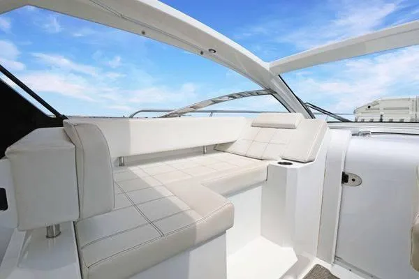 Slide: The Image of 2018 Cruisers Yachts 390 Express Coupe interior with white seating under a clear blue sky. - 24