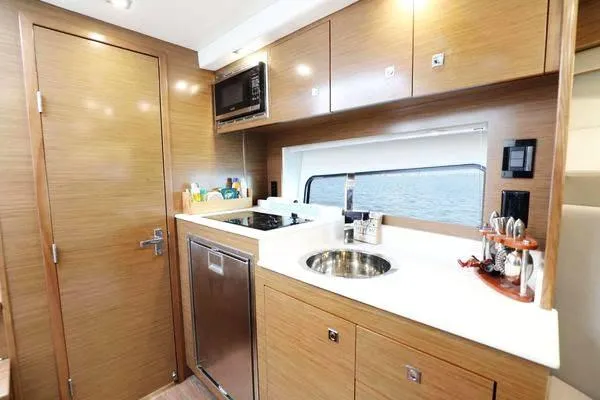 Slide: The Image of Modern kitchen interior of 2018 Cruisers Yachts 390 Express Coupe with wood cabinetry and stainless appliances. - 35