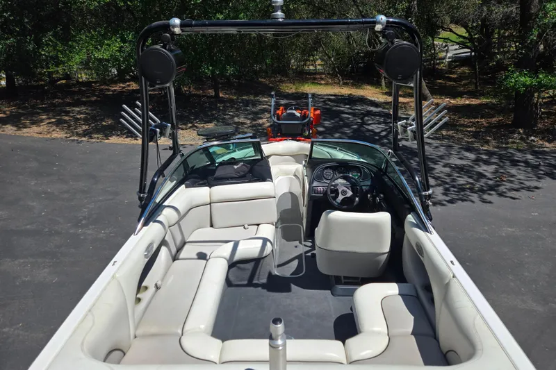 Slide: The Image of 2003 Malibu Sunscape 21 LSV boat interior with seating and steering wheel, parked outdoors. - 10