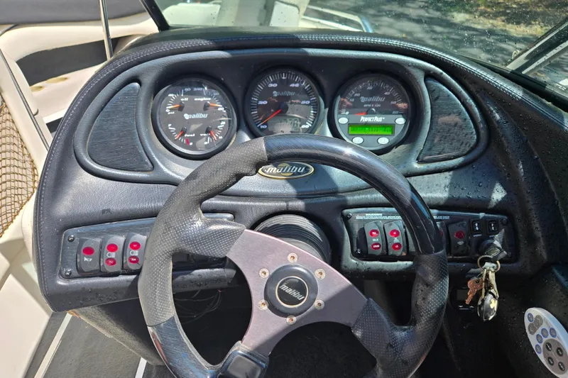 Slide: The Image of Dashboard of a 2003 Malibu Sunscape 21 LSV boat with steering wheel and gauges. - 14