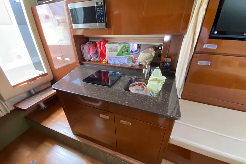Slide: The Image of Compact kitchen area in a 2003 Monterey 302 Cruiser boat with microwave and sink. - 46