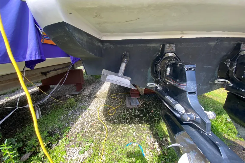 Slide: The Image of 2003 Monterey 302 Cruiser boat underside with dual MerCruiser outdrives on gravel surface. - 54