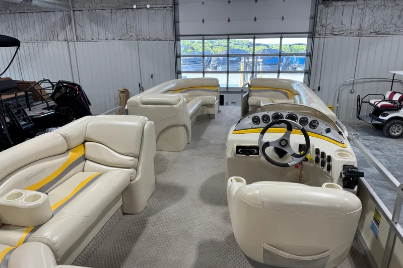 Slide: The Image of 2005 Bennington 2575 RL pontoon boat interior with beige seating and steering console. - 9
