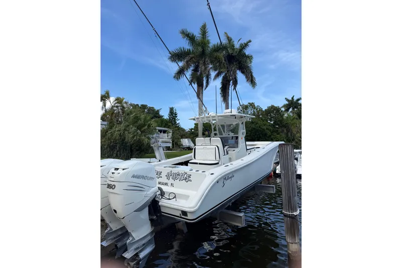 Slide: The Image of 2006 Yellowfin 34 Offshore boat docked, featuring twin Mercury 350 engines, surrounded by palm trees. - 34
