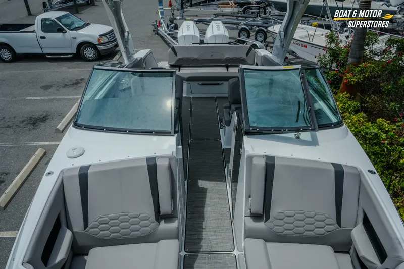 Slide: The Image of 2026 Four Winns H9 OB boat interior with seating and windshield, parked outdoors. - 16