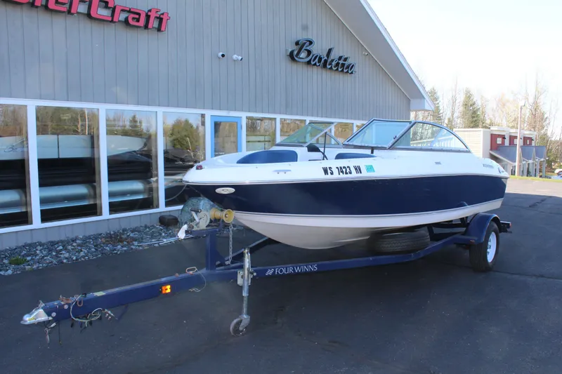 Slide: The Image of 2011 Four Winns H180 LE boat on trailer outside store. - 4