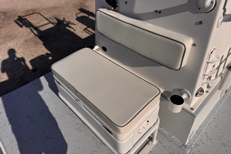 Slide: The Image of White cushioned seat on a 2006 Waterman K-18 boat, with shadows and textured flooring. - 23