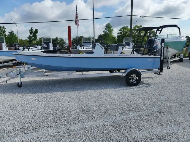 Slide: The Image of 2026 Xpress Skiff 185 boat on trailer, blue sky, gravel ground. - 4