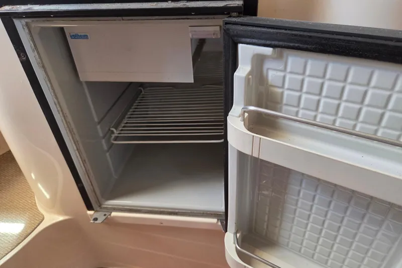 Slide: The Image of Open fridge inside a 2007 Grady-White Express 305 boat, showing interior shelves. - 22