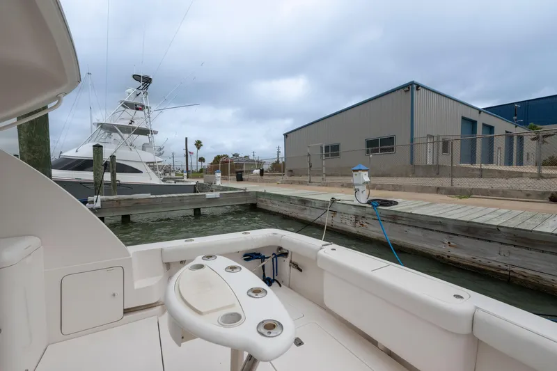 Slide: The Image of 2004 Bertram 390 Convertible yacht docked at marina with industrial buildings in background. - 10
