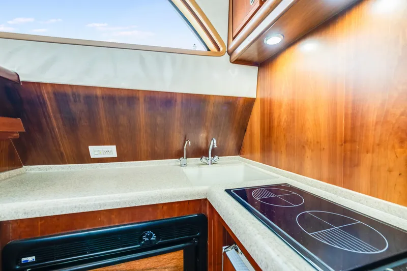 Slide: The Image of 2004 Bertram 390 Convertible yacht kitchen with wood paneling, sink, and electric stove. - 16