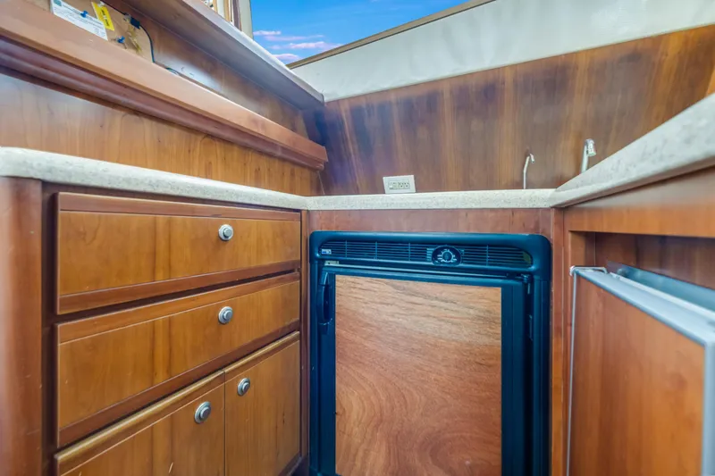 Slide: The Image of 2004 Bertram 390 Convertible yacht interior with wooden cabinetry and compact refrigerator. - 17