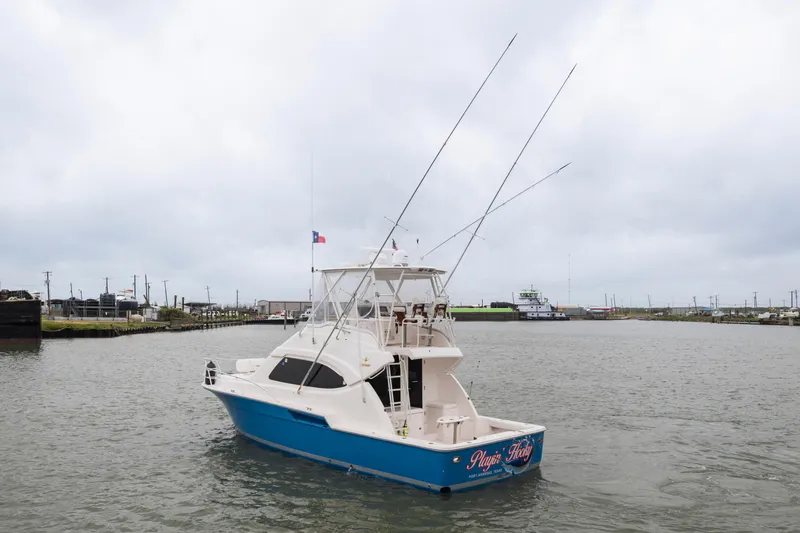 Slide: The Image of 2004 Bertram 390 Convertible boat on a calm waterway under cloudy skies. - 2
