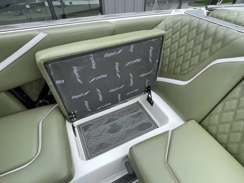 Slide: The Image of 2024 Tigé 24RZX interior with green upholstery and storage compartment. - 23