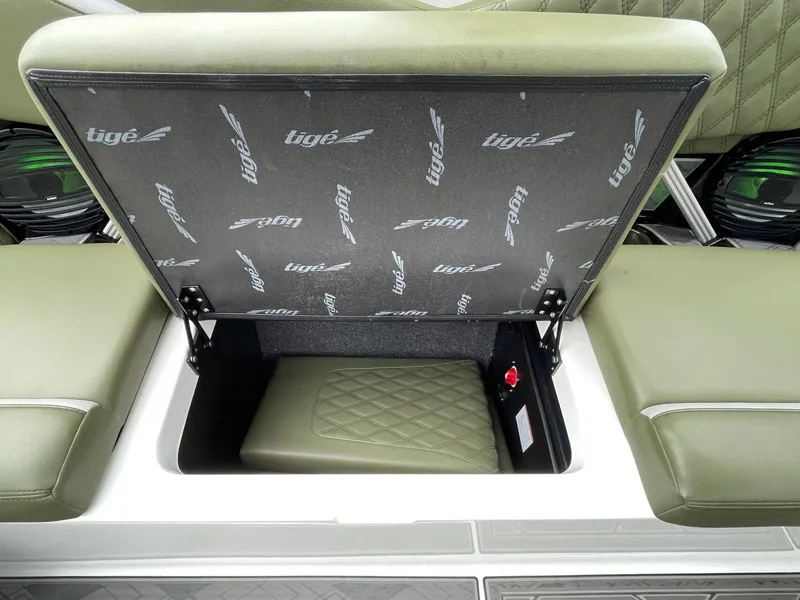 Slide: The Image of 2024 Tigé 24RZX boat with open storage compartment and green upholstery. - 24