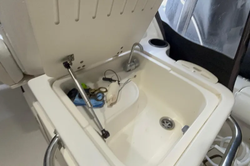 Slide: The Image of Open storage compartment on 2005 Boston Whaler 305 Conquest boat, showing various small items. - 24