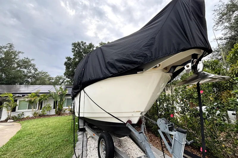 Slide: The Image of 2005 Boston Whaler 305 Conquest boat covered on trailer in residential yard. - 3