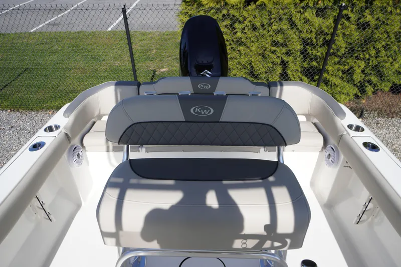 Slide: The Image of 2025 Key West 203 FS boat interior with seating and motor, parked near a fence. - 15
