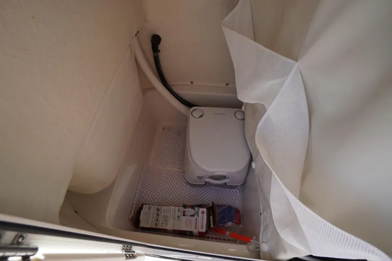 Slide: The Image of Interior of 2025 Key West 203 FS boat with compact toilet and storage area. - 26