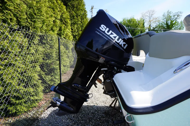 Slide: The Image of 2025 Key West 203 FS boat with Suzuki outboard motor, parked near a chain-link fence. - 3
