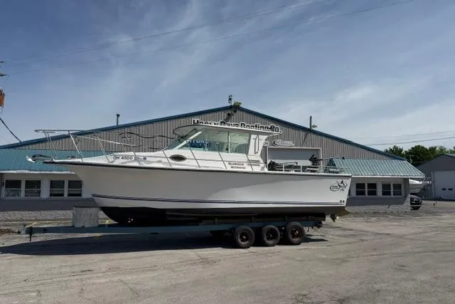 The Image of 2006 Baha Cruisers 300 GLE boat on trailer, parked outside a large building. - 0