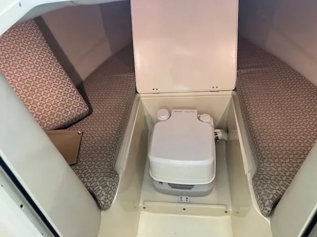 Slide: The Image of 2014 Chris-Craft Corsair 25 cabin interior with portable toilet and cushioned seating. - 21