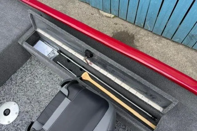 Slide: The Image of Storage compartment in 2025 Tracker Super Guide V-16 SC boat with fishing gear and paddle. - 12
