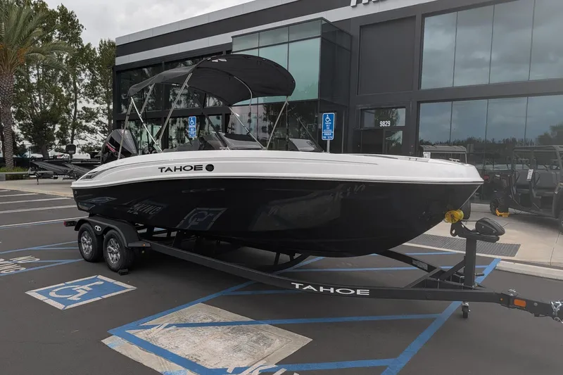 The Image of 2026 Tahoe T21 boat on trailer, parked outside dealership with glass facade. - 0