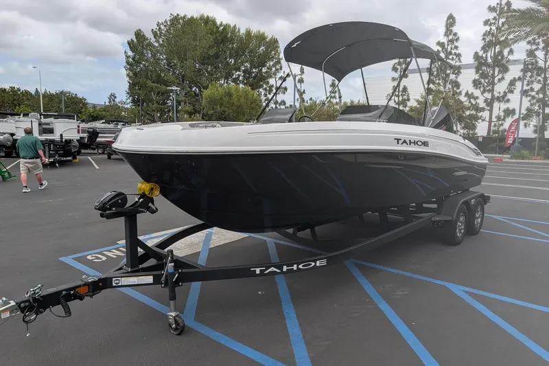 Slide: The Image of 2026 Tahoe T21 boat on trailer in parking lot, surrounded by trees and vehicles. - 1